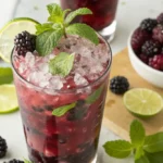 Blackberry mojito mocktail in a clear glass with mint, lime, and crushed ice